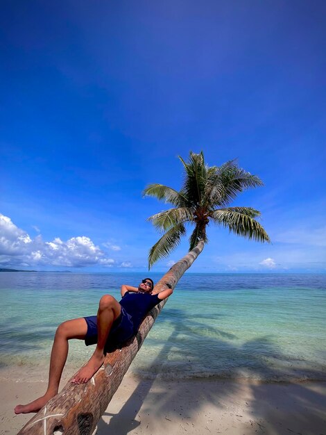 Foto hombre acostado en una palmera