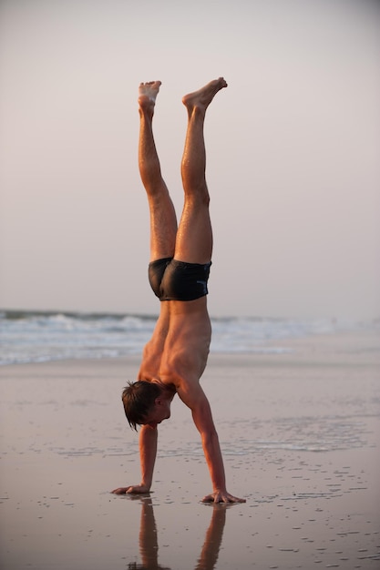 Hombre acróbata en la playa