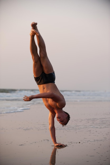 Hombre acróbata en la playa