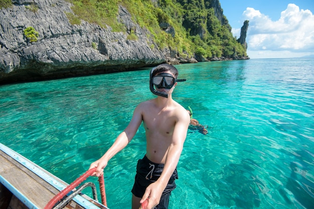 Foto un hombre activo en barco tradicional tailandés está listo para bucear y hacer snorkel, islas phi phi, tailandia