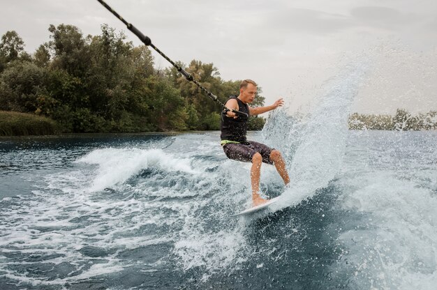 Hombre activo montando en el wakeboard con una cuerda