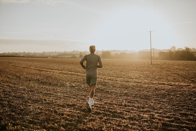 Hombre activo en ropa deportiva corriendo en el campo