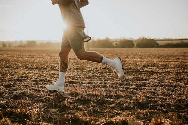 Hombre activo en ropa deportiva corriendo en el campo