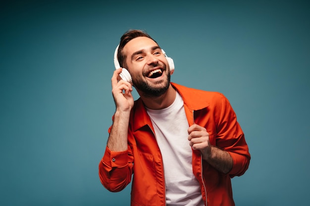 Hombre activo con traje naranja ríe y escucha música.