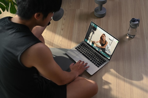 Hombre activo viendo lecciones de entrenamiento en línea y haciendo ejercicio en casa