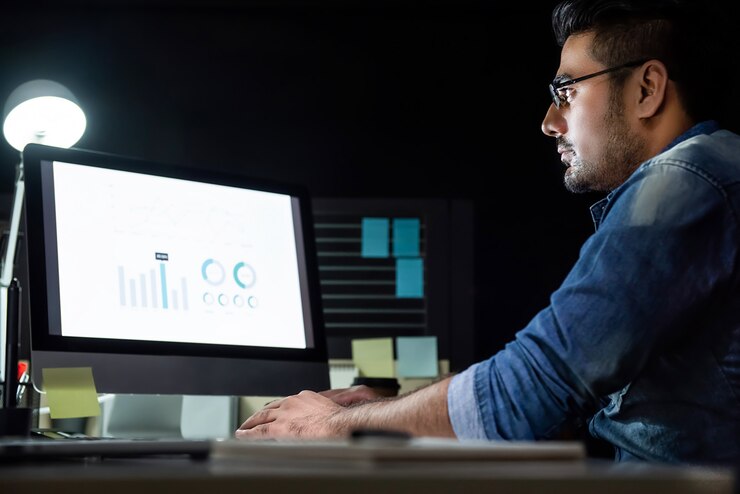 Foto hombre adicto al trabajo que trabaja horas extras por la noche en la oficina