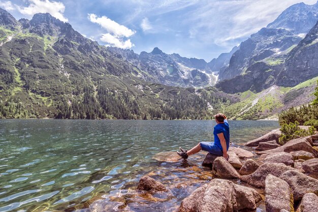 El hombre admira el paisaje de montaña en el lago