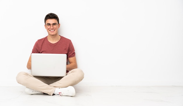 Hombre adolescente sentado en la flor con su computadora portátil
