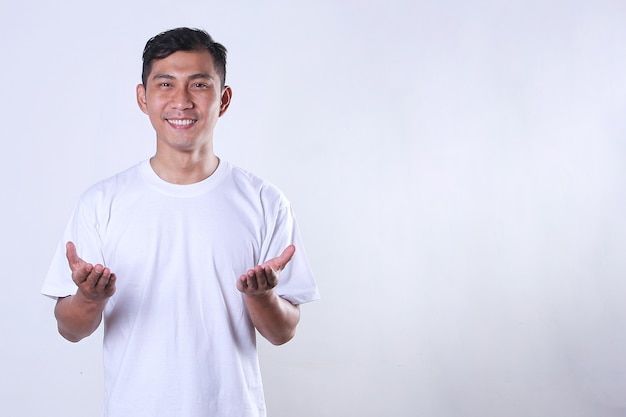 Un hombre adulto asiático con una camiseta blanca y abriendo los brazos con espacio de copia