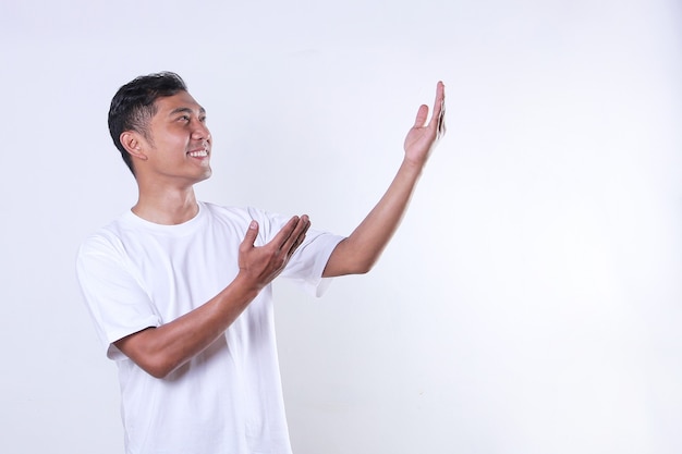 Un hombre adulto asiático con una camiseta blanca mira y abre los brazos hacia un lado con espacio de copia