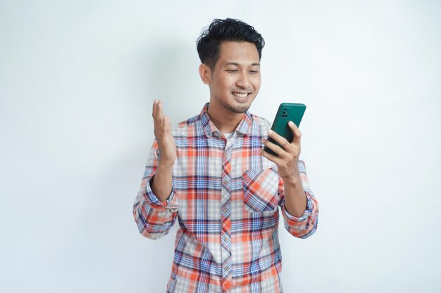 Foto hombre adulto asiático mirando su teléfono móvil con expresión feliz