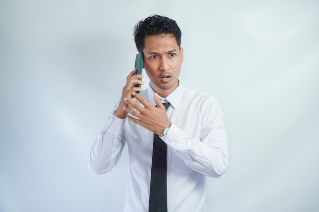 Foto hombre adulto asiático que muestra una expresión no feliz al responder una llamada telefónica