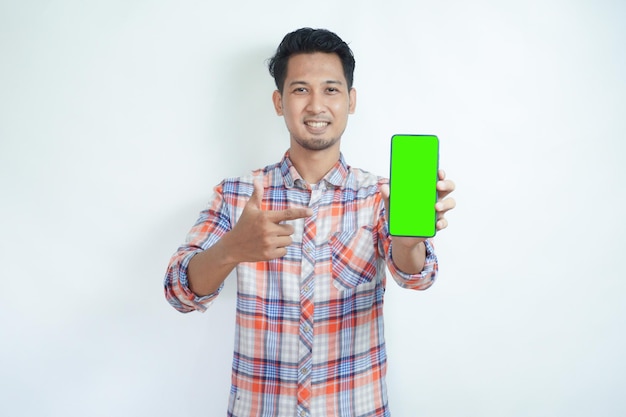 Foto hombre adulto asiático sonriendo feliz mientras muestra la pantalla verde del teléfono móvil y señala hacia ella