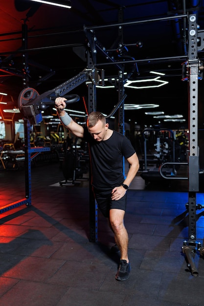 Hombre adulto atractivo haciendo ejercicios y levantando pesas en el gimnasio. Entrenamiento deportivo en el gimnasio