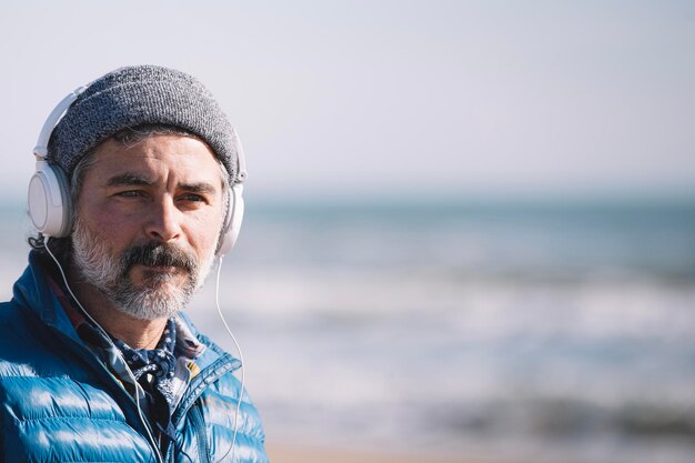 Hombre adulto con auriculares en el espacio de copia de playa