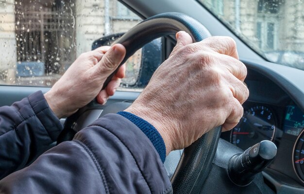 Hombre adulto en un automóvil de pasajeros sosteniendo la rueda de dirección