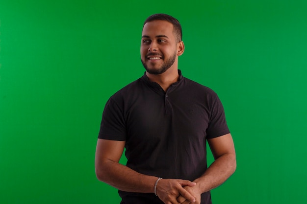 Foto hombre adulto con barba pequeña con camisa negra en una foto de estudio con fondo verde