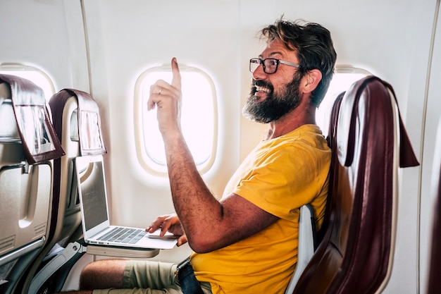 Hombre adulto caucásico barbudo sentarse dentro del vuelo del avión pidiendo ayuda a la azafata