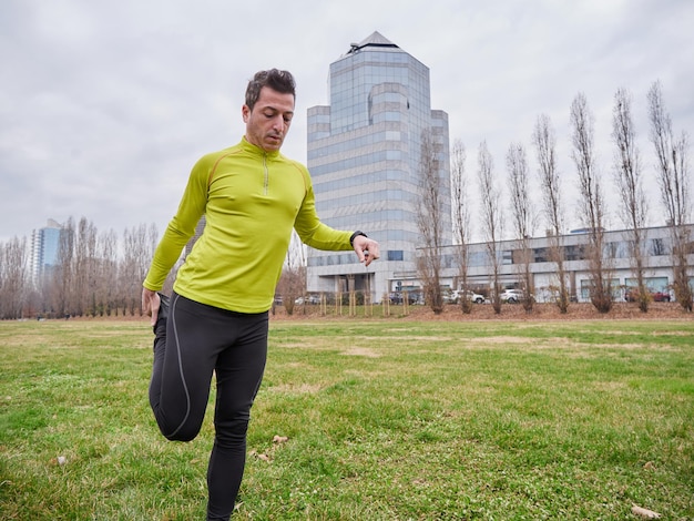 Hombre adulto corriendo en el parque en invierno con el fondo de la ciudad