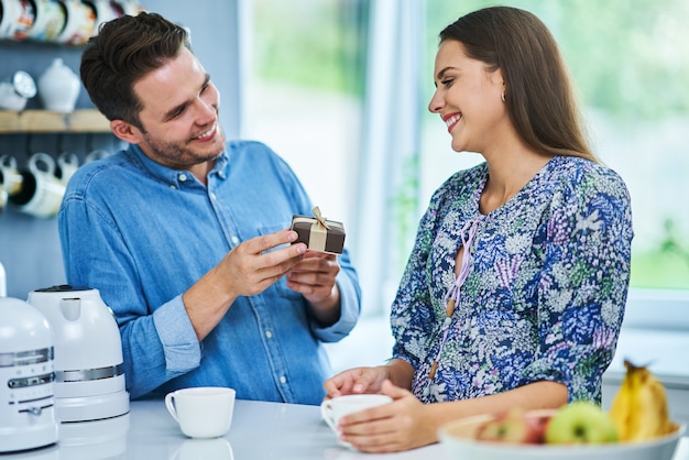 Hombre adulto dando presente a su esposa en la cocina