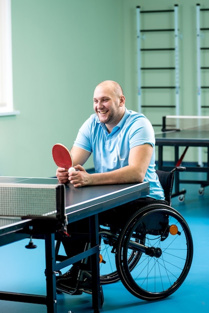 Hombre adulto discapacitado en silla de ruedas, formación antes de jugar al tenis de mesa