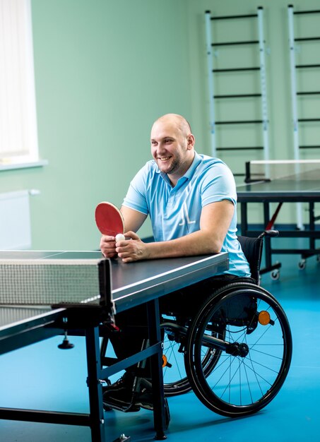 Hombre adulto discapacitado en silla de ruedas, formación antes de jugar al tenis de mesa