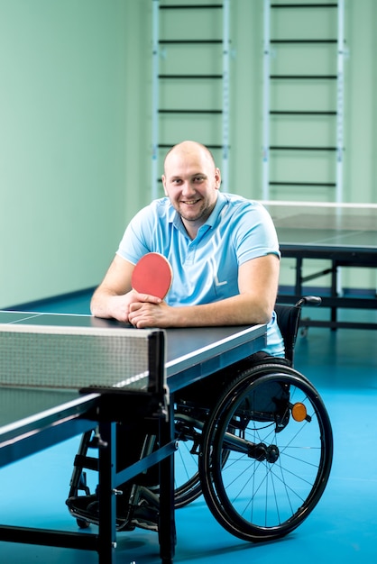 Hombre adulto discapacitado en silla de ruedas, formación antes de jugar al tenis de mesa