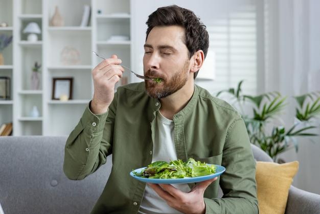 Hombre adulto disfrutando de una ensalada fresca en una sala de estar moderna