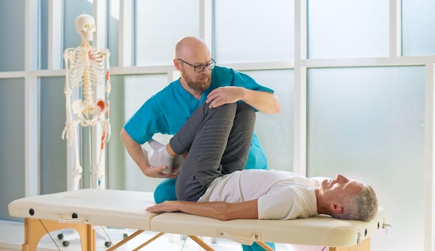 Un hombre adulto entrena fuerza muscular con un médico profesional en una clínica de rehabilitación moderna phy