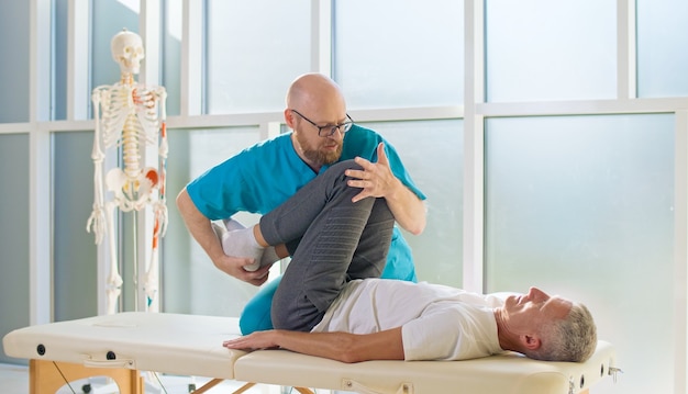 Un hombre adulto entrena la fuerza muscular con un médico profesional en una moderna clínica de rehabilitación.