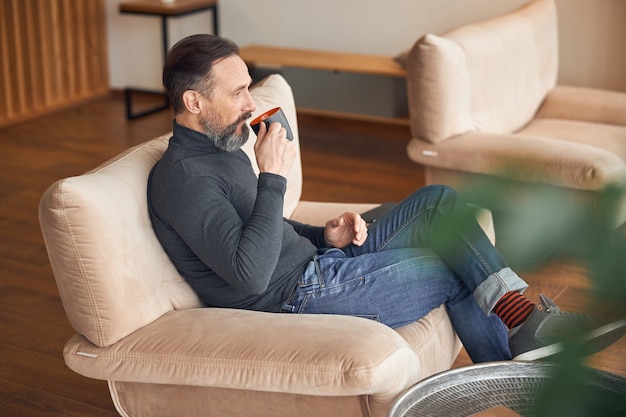 Hombre adulto está sentado en una zona de salón y relajándose