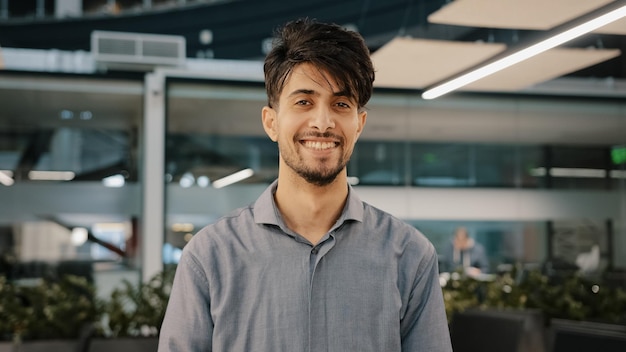 Hombre adulto guapo con barba india feliz parado en la oficina del pasillo sonriendo mirando a la cámara hombre alegre