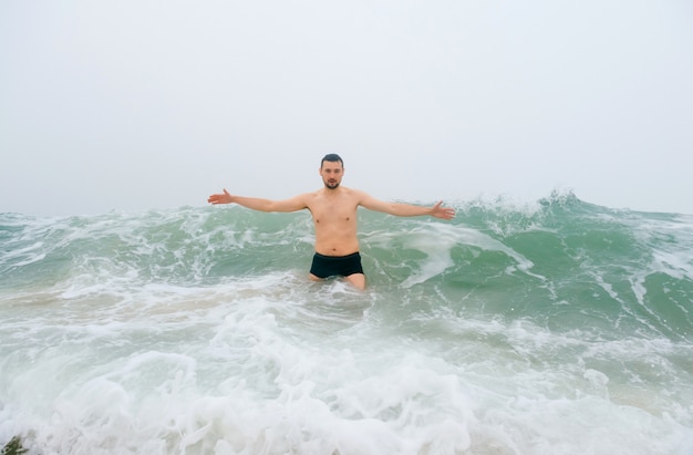 Hombre adulto intrépido disfrutando en mar frío tormentoso