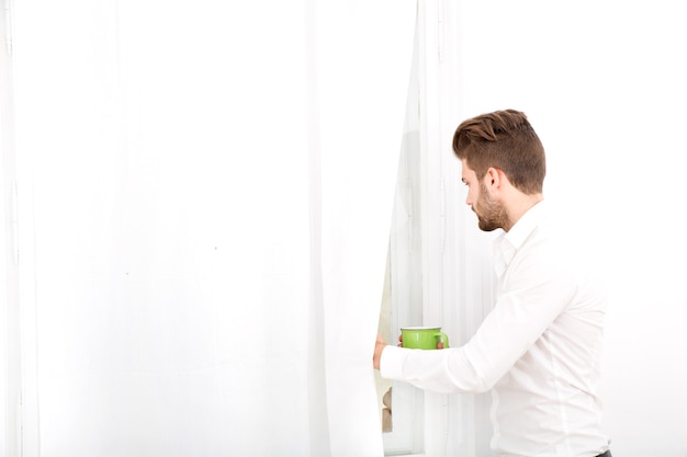 Un hombre adulto joven en casa tomando café.