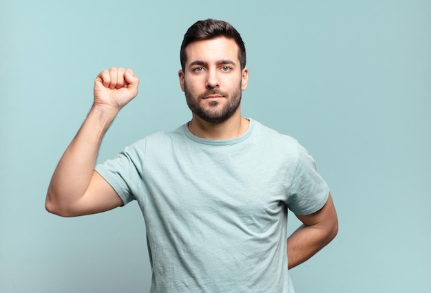 Hombre adulto joven guapo que se siente serio, fuerte y rebelde, levantando el puño, protestando o luchando por la revolución