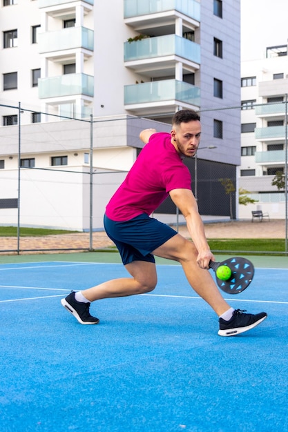 Foto hombre adulto joven jugando pickleball retrato de un hombre realizando un tiro de revés en un partido de pickleball