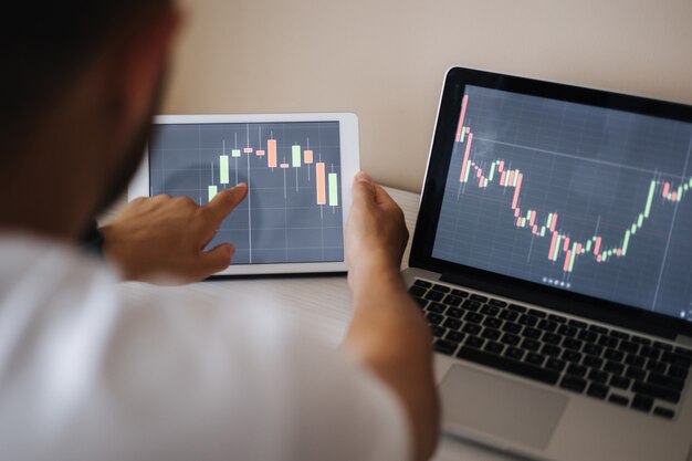 Hombre adulto joven que comercia en línea con tablet pc conectado a la bolsa de valores personas financian inversiones