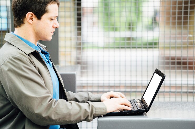 Foto hombre adulto joven que trabaja en la calle con una pequeña computadora portátil. concepto de tecnología para llevar. conectividad portátil