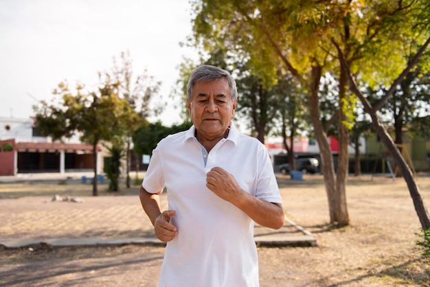 Hombre adulto mayor corriendo frente a la cámara haciendo ejercicio en el parque