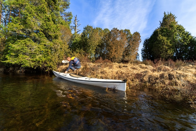 Hombre adulto mayor a punto de entrar en su kayak blanco