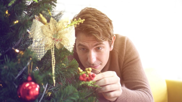 Hombre adulto medio decorando el árbol durante la Navidad