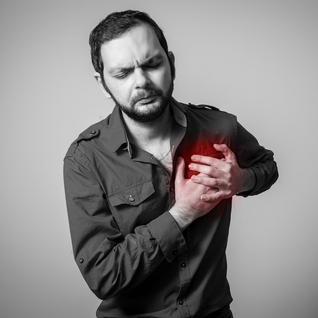 Foto hombre adulto medio que sufre de dolor en el pecho contra un fondo gris