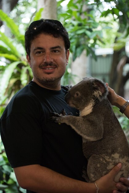 Hombre adulto medio sosteniendo un oso koala