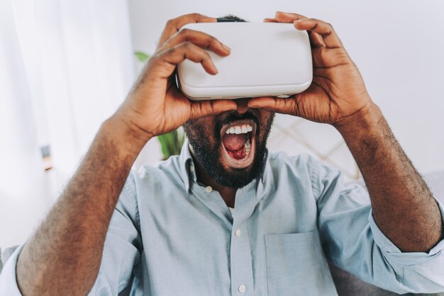 Hombre adulto negro guapo en casa jugando con auriculares vr