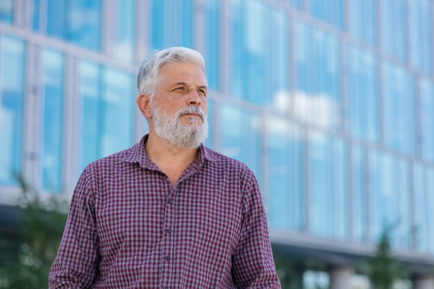 Un hombre adulto de pelo gris con barba va a la oficina a trabajar a un hombre de negocios senior en una camisa