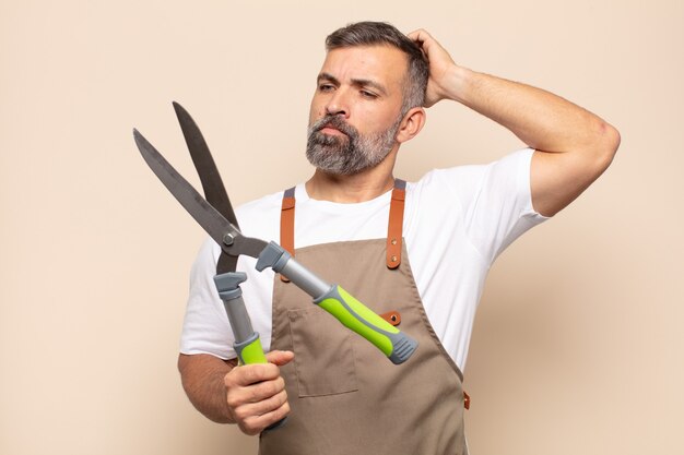 Hombre adulto que se siente desconcertado y confundido, rascándose la cabeza y mirando hacia un lado