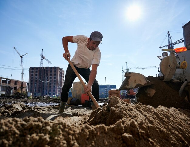 Hombre adulto que trabaja con mortero de cemento fuera del objeto de construcción