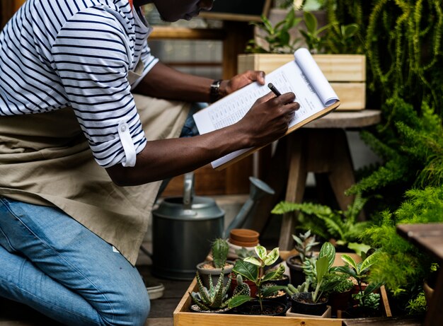 Hombre adulto revisando plantas fuera de la tienda de flores