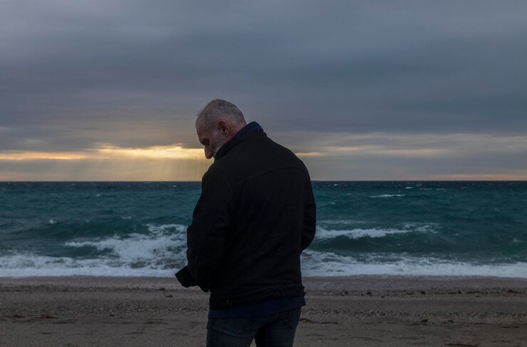 Foto hombre adulto con ropa de invierno en la playa durante la puesta de sol almeria españa