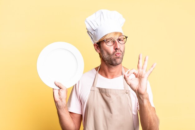 Hombre adulto rubio guapo chef con un plato vacío